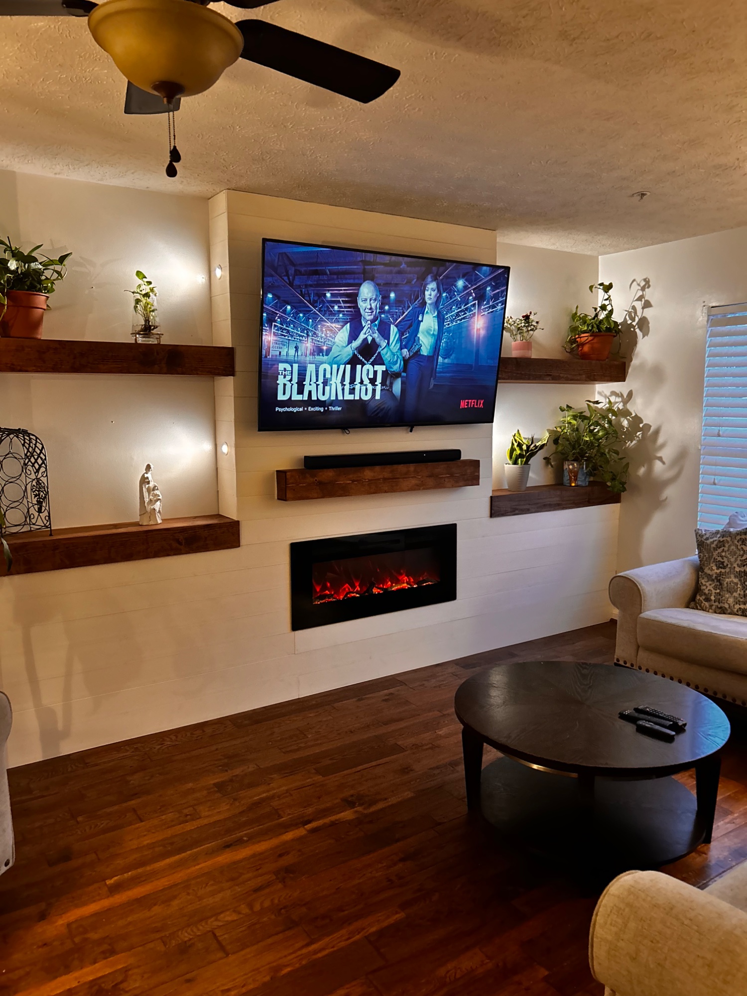Media wall with custom built shelving, adjustable lighting, fireplace, and mantle.