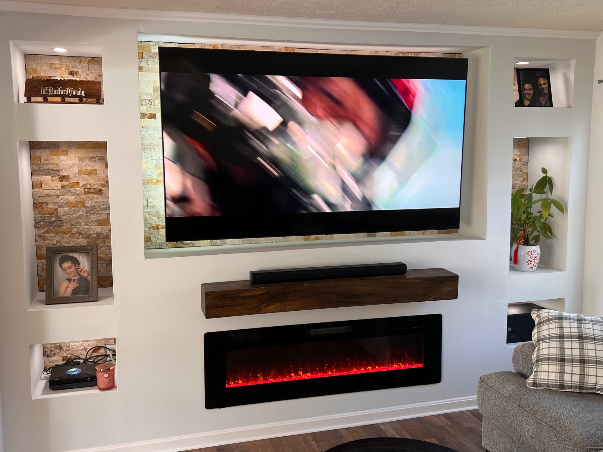 Custom built drywall media wall with stone backdrop, led medial light surround tv that adjust with tv picture, recessed adjustable light, fireplace, and mantle